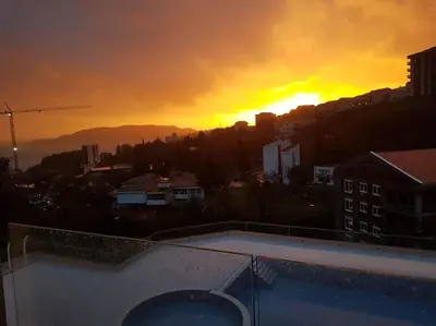 a sunset over a city with a swimming pool at Стильная квартира с видом на море и библиотекой in Becici