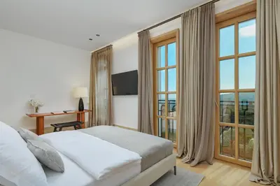 a bedroom with a bed and a desk and windows at Eterno Villas in Budva