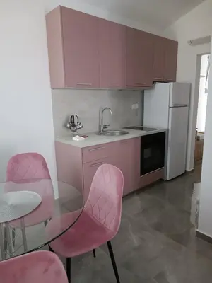 a kitchen with pink chairs and a glass table at Luna Apartment in Kotor