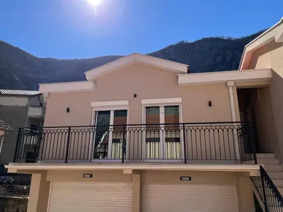 a house with a balcony with a mountain in the background at Luna Apartment in Kotor
