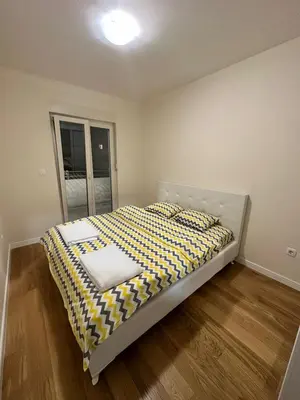 a bedroom with a bed with a yellow and white comforter at Apartman VT 2 Central point in Podgorica
