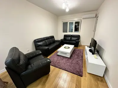 a living room with black leather furniture and a tv at Apartman VT 2 Central point in Podgorica