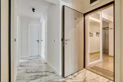 a hallway with a glass door and marble floor at Apt 