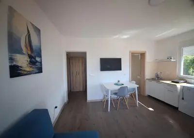 a living room with a white table and a kitchen at Apartmani Seaview in Sutomore