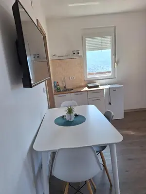 a small kitchen with a white table and chairs at Apartmani Seaview in Sutomore