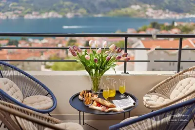 a table with a vase of flowers and drinks on a balcony at Condo Cattaro in Kotor