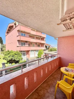 a balcony with a yellow table and a pink building at Apartments Zeneva in Donji Štoj