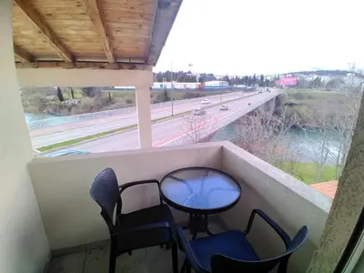 a table and chairs on a balcony with a view of a highway at Apartman Podgorica Stara Varos Vlado in Podgorica