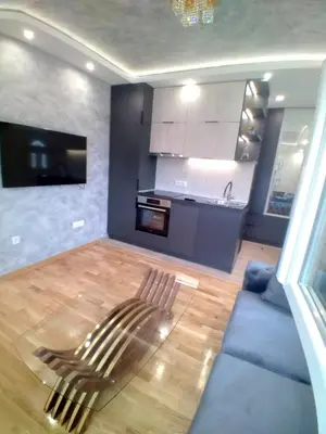 a living room with a blue couch and a kitchen at Apartman Podgorica Stara Varos Vlado in Podgorica