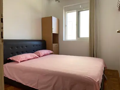 a bedroom with a bed with pink sheets and a window at Apartmani centar ulcinj in Ulcinj