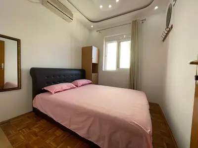 a bedroom with a bed with pink sheets and a window at Apartmani centar ulcinj in Ulcinj