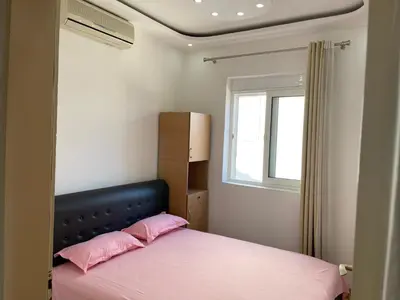 a bedroom with a bed with pink pillows and a window at Apartmani centar ulcinj in Ulcinj