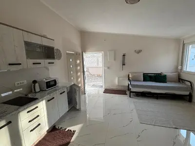 a kitchen with white cabinets and a couch in a room at Villa Tunaj new Pool and BBQ in Bar
