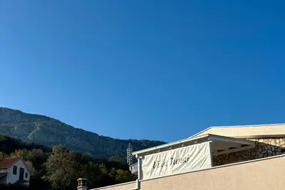a sign on the side of a building with mountains in the background at Villa Tunaj new Pool and BBQ in Bar