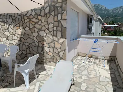 a patio with white chairs and a stone wall at Villa Tunaj new Pool and BBQ in Bar