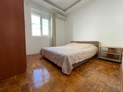 a bedroom with a bed and a window and a wooden floor at Aprtmani centar 2 in Ulcinj