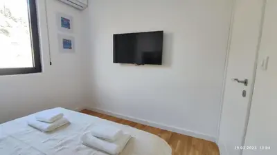a white room with a bed with two white towels at Apartments LORA in Bonila in Rafailovici