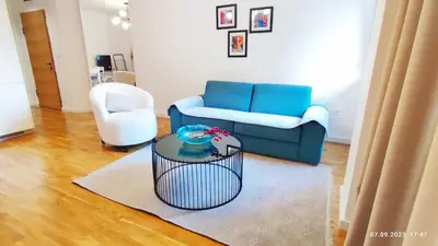 a living room with a blue couch and a table at Apartments LORA in Bonila in Rafailovici