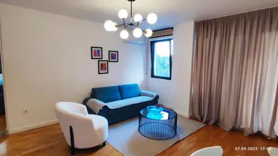 a living room with a blue couch and a chair at Apartments LORA in Bonila in Rafailovici