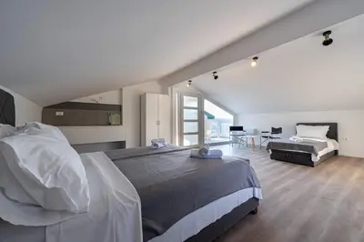 a bedroom with a large bed and a room with a couch at Regina Residence in Budva