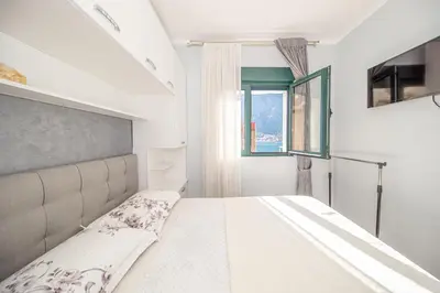 a bedroom with a large white bed with a window at Lena apartment 2 in Kotor