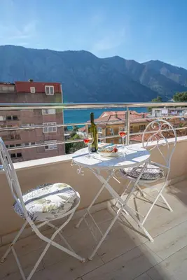a table and chairs on a balcony with a bottle of wine at Lena apartment 2 in Kotor