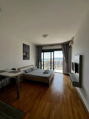 a bedroom with a bed and a table and a large window at Paradise Apartments Becici in Becici