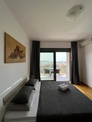 a bedroom with a bed and a view of a table at Paradise Apartments Becici in Becici