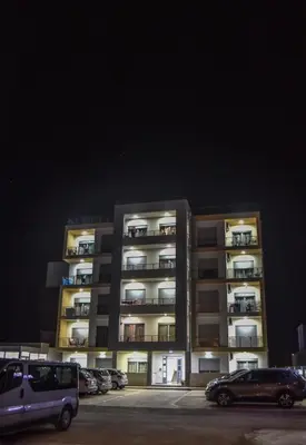 a large apartment building with cars parked in a parking lot at Dineta Apartment in Ulcinj
