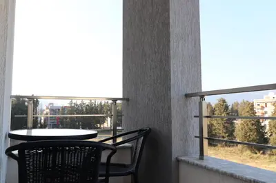 a balcony with two chairs and a table and a window at Dineta Apartment in Ulcinj