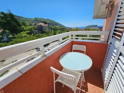 a table and chairs on the balcony of a house at Dom M Apartments in Budva