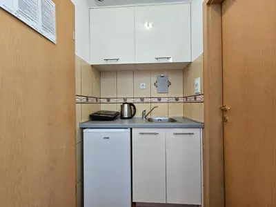 a small kitchen with white cabinets and a sink at Dom M Apartments in Budva