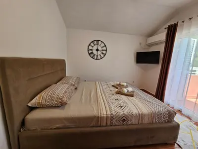 a bedroom with a bed and a clock on the wall at Dom M Apartments in Budva
