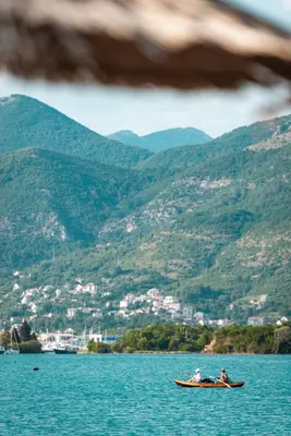 two people in a boat in the water with mountains at Aquata Apartments in Tivat