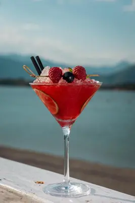a drink with berries in a martini glass on a table at Aquata Apartments in Tivat