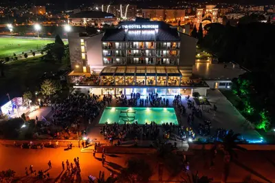 a crowd of people standing in front of a building at night at Hotel Princess in Bar
