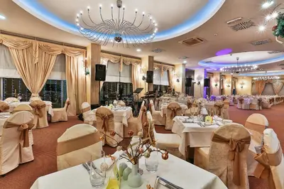 a restaurant with white tables and chairs and a chandelier at Hotel Princess in Bar