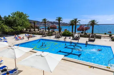 a large swimming pool with umbrellas and the ocean at Hotel Princess in Bar