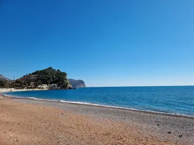 a beach with blue water and a rocky shore at Seaview Apartments VERA in Petrovac na Moru