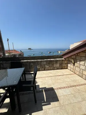 a table and chairs on a patio with a view of the ocean at Seaview Apartments VERA in Petrovac na Moru