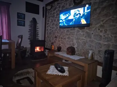 a living room with a tv on a stone wall at Apartments 