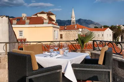 a table with wine glasses on top of a balcony at Hotel Astoria in Budva