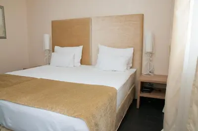 a bedroom with a large bed with white sheets and pillows at Hotel Astoria in Budva