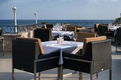 a restaurant with tables and chairs with the ocean in the background at Hotel Astoria in Budva
