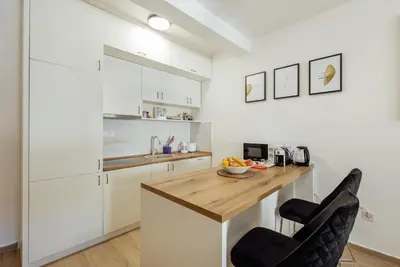 a kitchen with white cabinets and a wooden counter top at APARTLU in Kotor