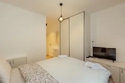 a bedroom with a white bed and a large mirror at APARTLU in Kotor