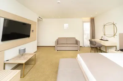 a hotel room with a bed and a couch and a television at Hotel Pima Budva in Budva