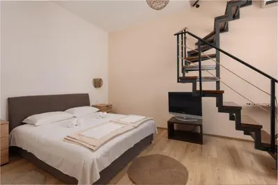 a bedroom with a bed and a spiral staircase at Apartman Oasis in Kotor