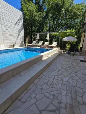 a swimming pool with chairs and an umbrella at Apartments TP 777 in Budva