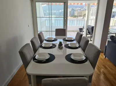 a dining room table with chairs and a large window at Top floor with stunning seaview, first line in Rafailovici